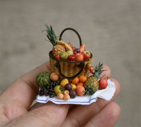 A Hand Holding A Miniature Basket Filled With Fruit