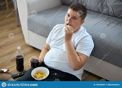 Overweight Fat Boy Eat Junk Food While Watching Tv Alone At Home Stock