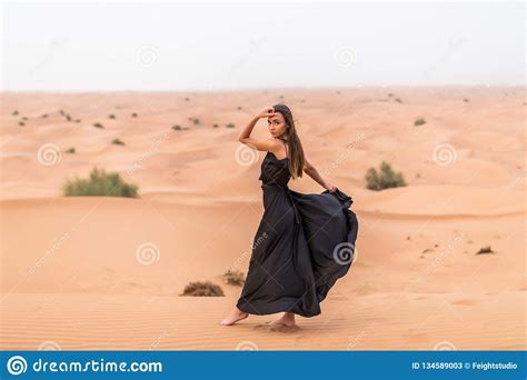 Beautiful Pretty Woman In Black Dress On A Sand Dune Of Desert Stock