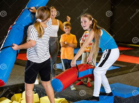 teenage girl fighting by pugil sticks with little sister on inflatable beam stock image image