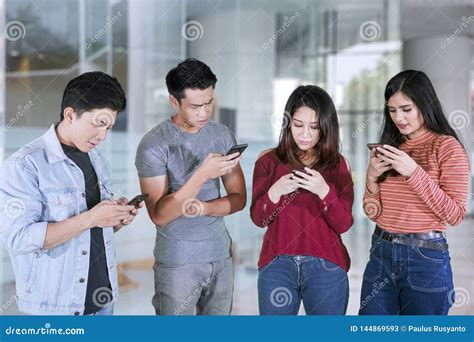 Four Young People Looks Busy With Mobile Phones Stock Image Image Of