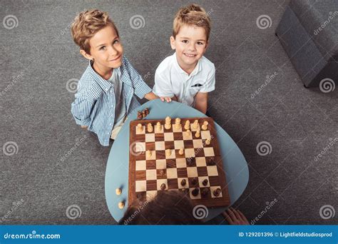 High Angle View Of Little Boys Playing Chess And Smiling At Camera