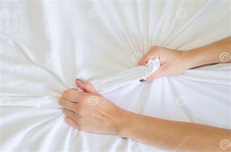 hand sign orgasm of woman on white bed hand of female pulling white sheets in ecstasy