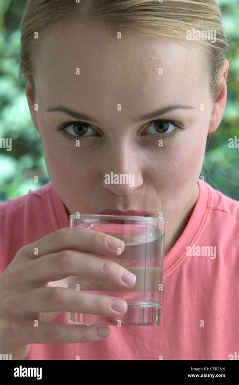 Female Blonde Hair Off Face Wearing Pink T Shirt Drinking Glass Of