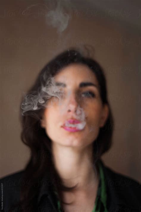 attractive woman blowing a cigarette smoke by stocksy contributor mak stocksy