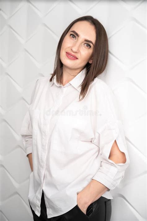 Beautiful Young Happy Woman Posing Against A White Brick Wall