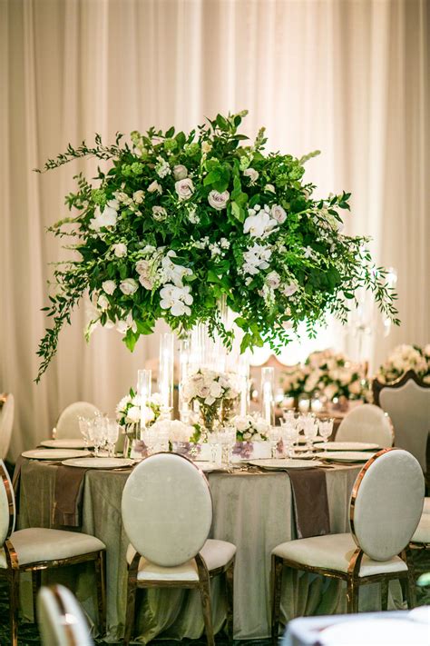 Tall Centerpieces Of Lush Greenery And White Florals Surrounded With