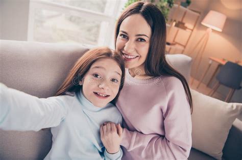 Photo Of Optimistic Brunette Red Hairdo Mom Daughter Hold Hands Do Selfie Sit On Sofa Wear