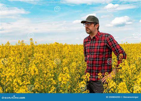 Confident And Self Assured Farm Worker Wearing Red Plaid Shirt And Trucker`s Hat Standing In