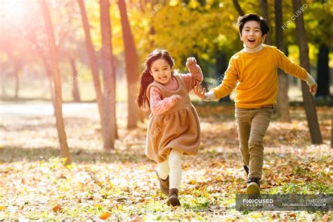 Adorable Happy Asian Children Running Together In Autumn Forest