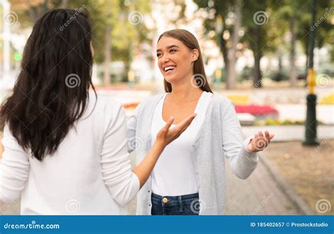 Two Happy Girls Greeting And Talking Meeting In Park Outdoor Stock