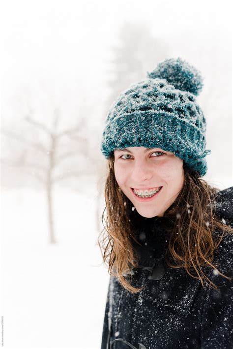 Portrait Of Smiling Teen Girl With Wool Hat In The Snow By Stocksy