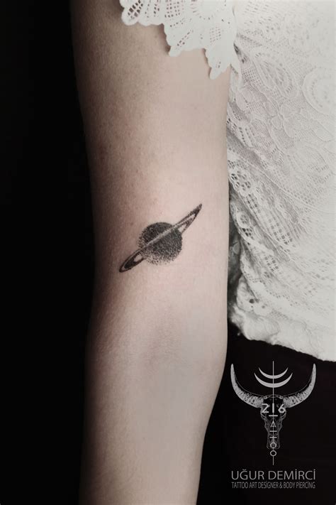 A Womans Arm With A Small Saturn Tattoo On The Left Side Of Her Arm