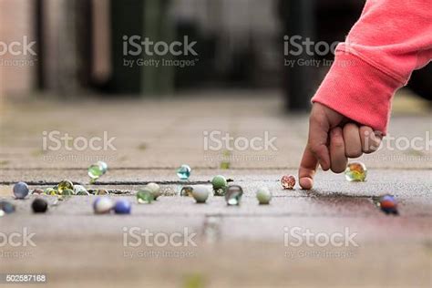 Child Playing With Marbles On The Sidewalk Stock Photo Download Image