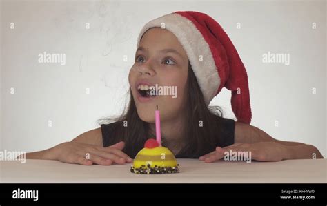 Beautiful Naughty Girl Teenager In A Santa Claus Hat Blows Out A Candle On A Festive Cake On