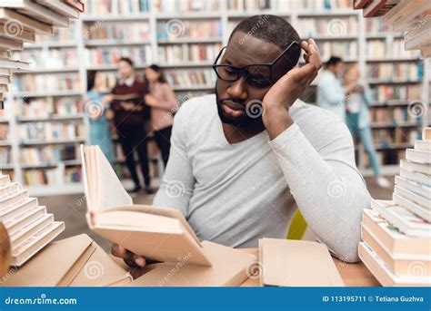 Ethnic African American Guy Surrounded By Books In Library Student Is