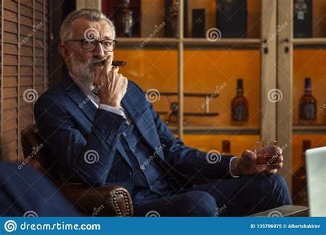 Elderly Businessman With Glass Of Whiskey And Cigar On Dark Background