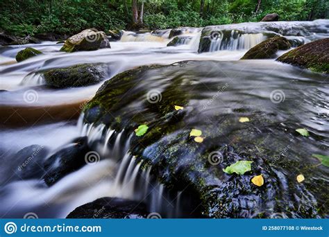 Long Exposure Shot Of A Waterfall Flowing Over Mossy Rocks In A Forest