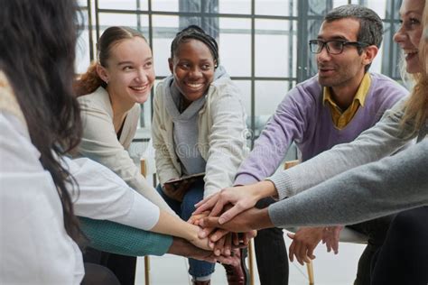 Diverse People Sitting In Circle Holding Hands At Group Therapy Stock
