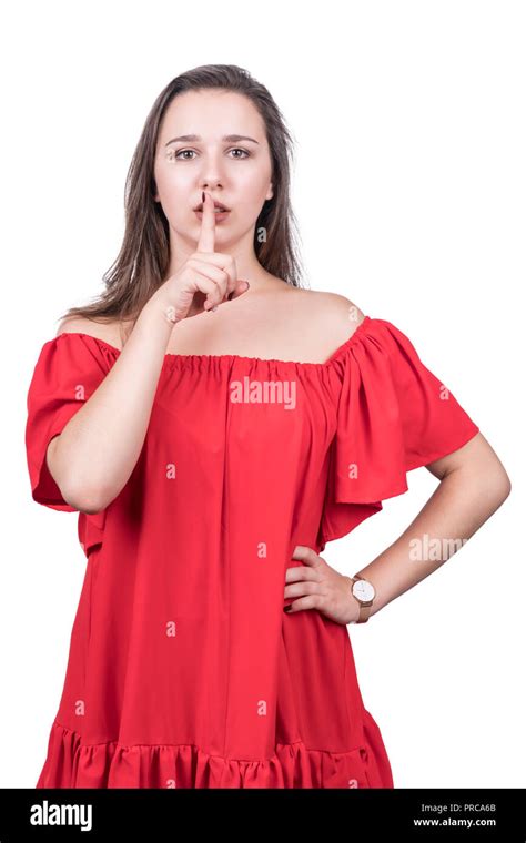 beautiful woman in red dress asks for silence holding a finger near her mouth isolated on