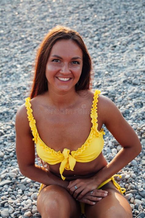 Beautiful Tanned Woman In Yellow Swimsuit Sunbathes On The Beach Stock