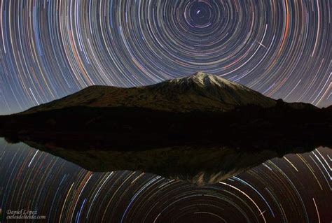 The Night Sky Is Filled With Star Trails And Stars Above A Small