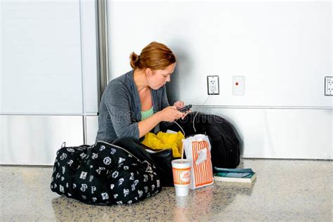 Kvinna Som Placeras På Golvet Som Laddar Hennes Telefon I En Flygplats Redaktionell Arkivfoto