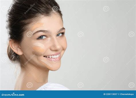 beautiful girl on light grey background using concealers and foundation for face contouring