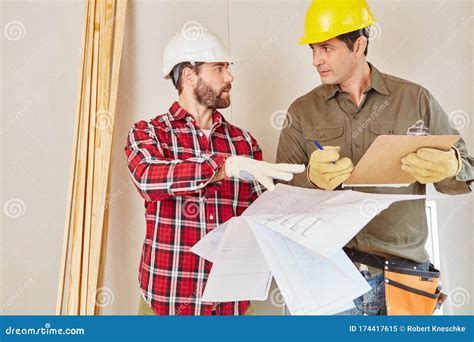 Architect And Foreman With Construction Drawing During Planning Stock