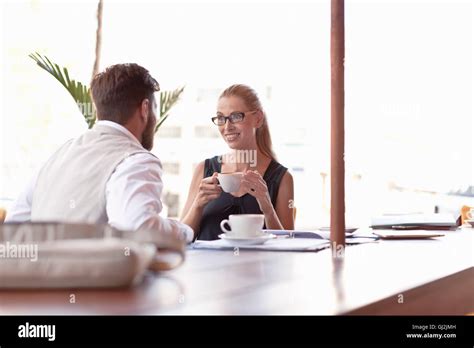 Mature Man And Woman Sitting Outside Cafe Drinking Coffee Face To