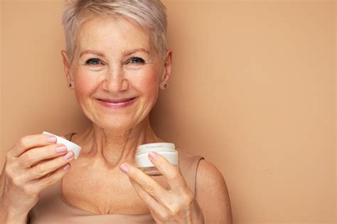Smiling 60s Middle Aged Mature Woman Putting Tightening Facial Cream On