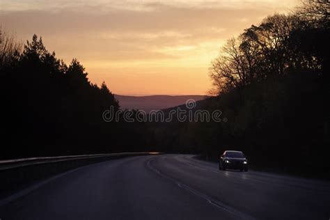 Road With Car Drive In Mountains Forest On Sunset Sky Stock Image
