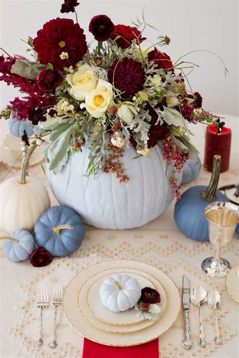 A White Pumpkin Decorated With Red And Yellow Flowers Sits On A Table