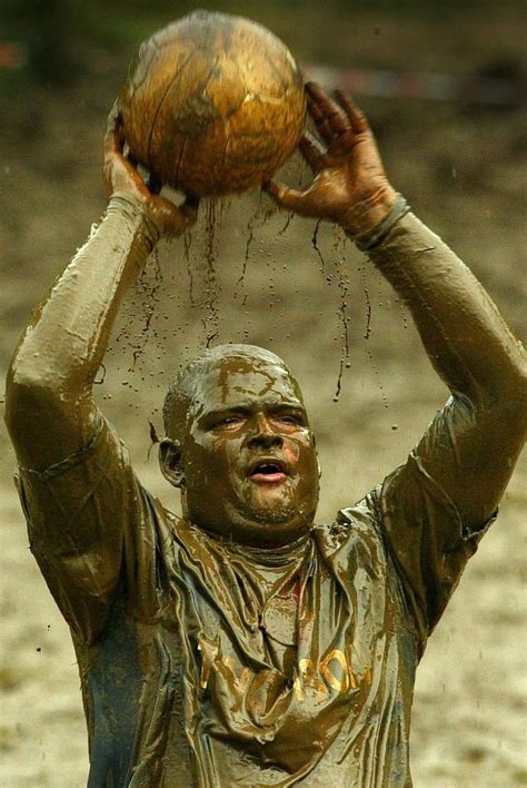 A Muddy Swamp Football Player Takes A Throw In On A Marshland Pitch In