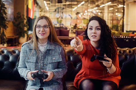 Two Girlfriends Play Video Games Holding Joysticks In Their Hands