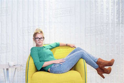 Serious Caucasian Woman Sitting In Yellow Chair Stock Photo Dissolve