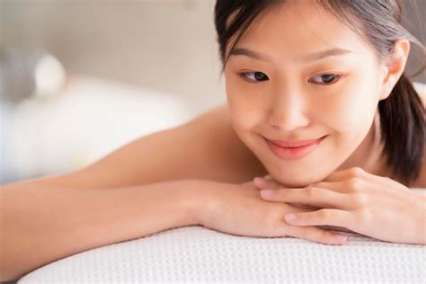 atractiva mujer asiática disfruta y almeja terapia de masaje oriental cama blanca concepto de