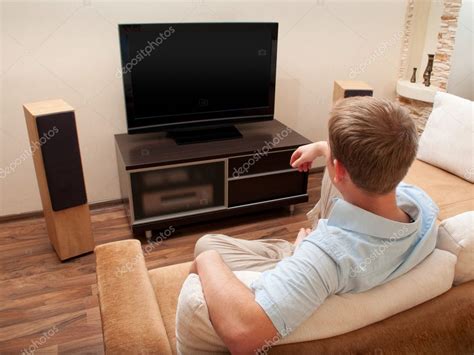 Hombre acostado en el sofá viendo la televisión en casa fotografía de stock luckyraccoon