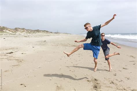 Two Young Men Frolicking On The Beeach By Stocksy Contributor Amy