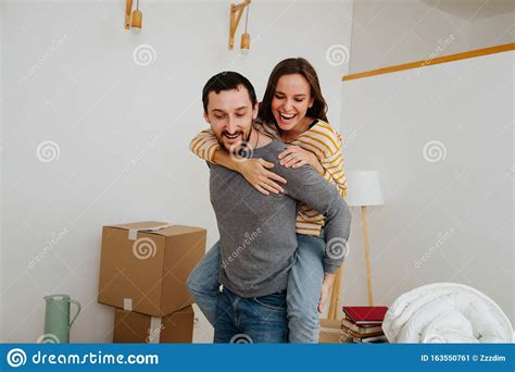 Couple Celebrating Moving Into A New Apartment Woman Riding On Her Man
