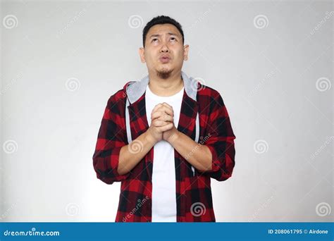 Young Asian Man Looking Up And Grasping His Hands Worried Expression