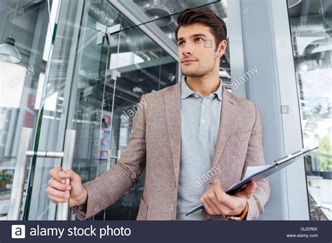 Attractive Young Businessman Holding Clipboard And Entering The Door In