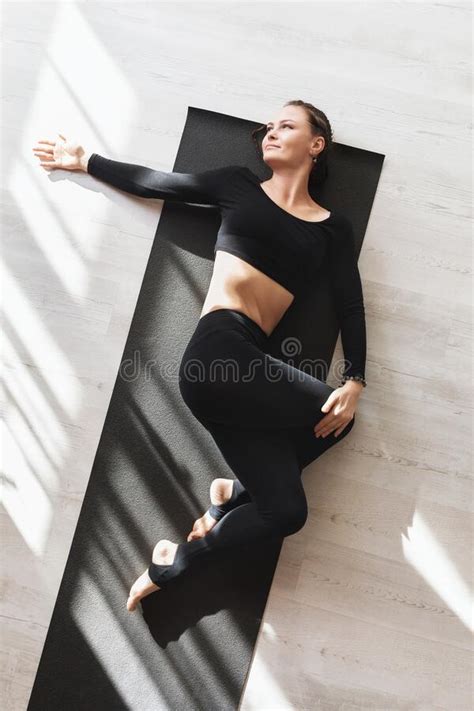 A Woman In Black Sportswear Practicing Yoga While Lying On A Gymnastic