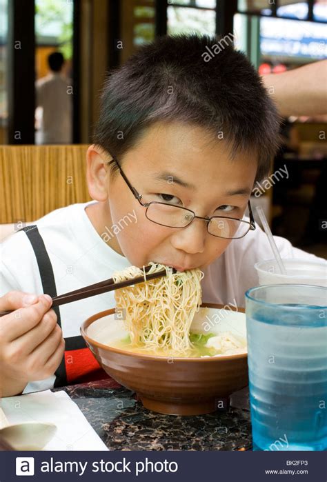 10 minutes, just 352 calories for a big bowl. Chinese boy eating ramen noodles and shrimp wonton soup ...