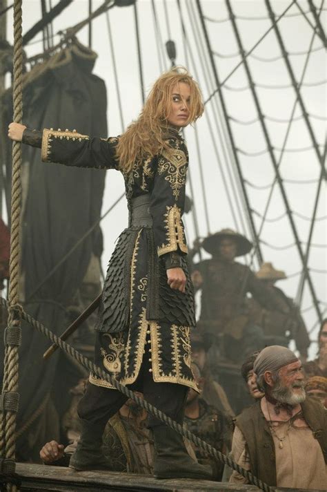 A Woman Dressed In Black And Gold Standing On Top Of A Boat With Her