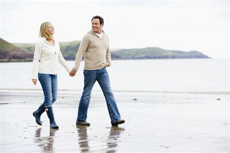 Couple Walking On Beach Holding Hands Smiling Amac Broker Services