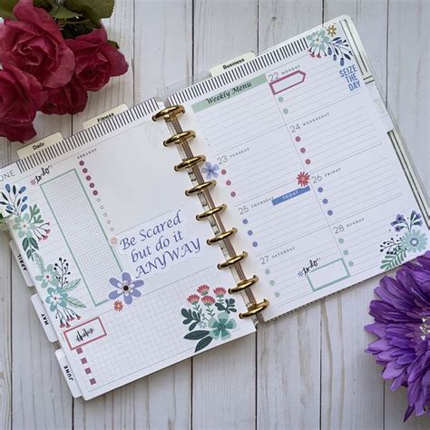 An Open Planner Book Sitting On Top Of A Wooden Table Next To Flowers