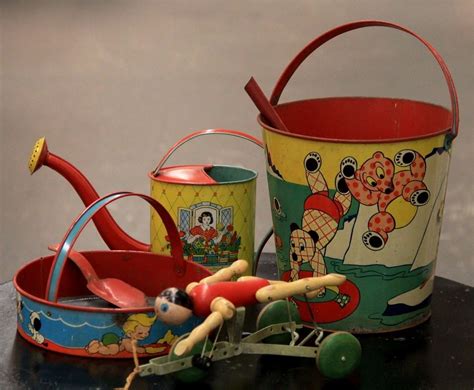 An Old Fashioned Tin Toy Is Sitting On A Table Next To Two Buckets And