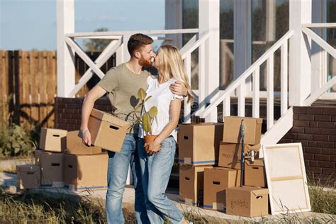 Husband And Wife Standing In Front Of New Buying Home With Boxes Stock