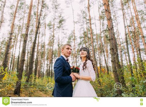 Happy Newlywed Bride And Groom Holding Hands Together In The Autumn